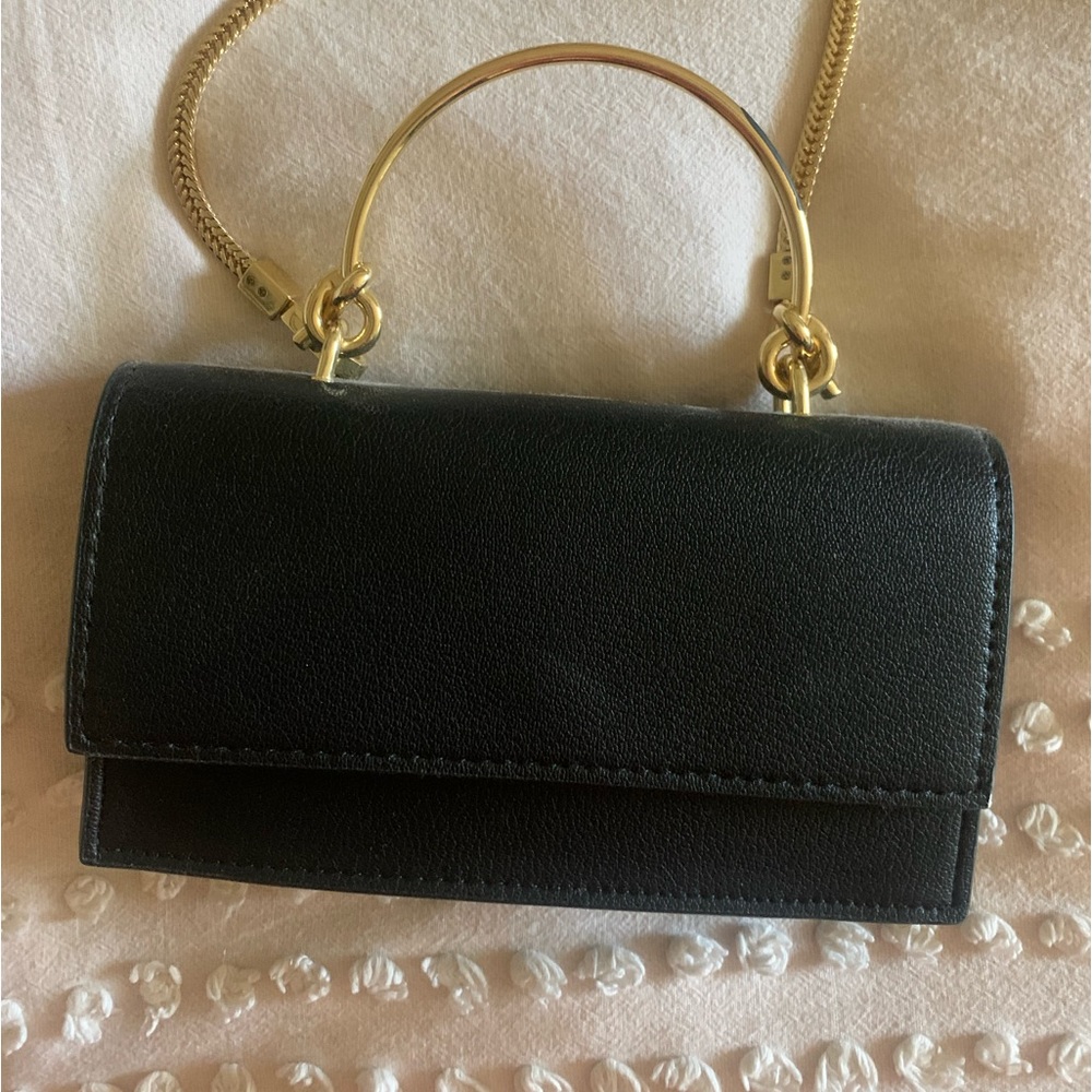 Black purse with gold handle and adjustable shoulder strap